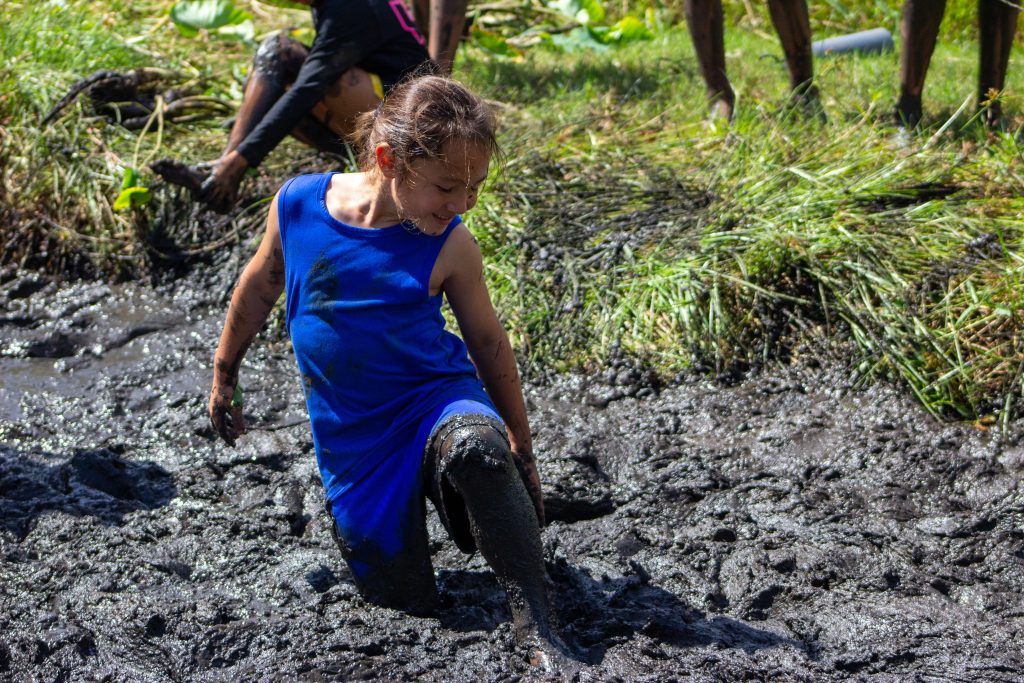 keiki walking through knee deep mud in a loʻi kalo