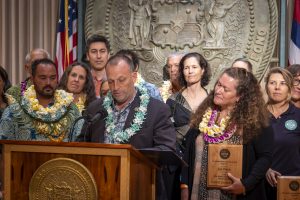 Kaua'i MVP Awardee, Lei Wann, watches as Governor Green signs the HISAM 2024 proclamation designating May as Hawai'i Invasive Species Awareness Month. 