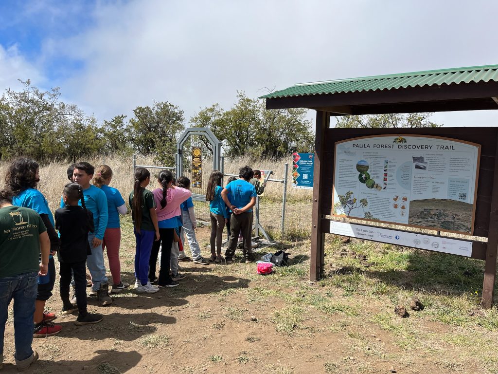 Student lined up to use the bootbrush at Palila Forest Discovery Trail before entering the trail through the gate.